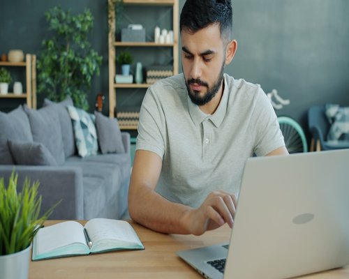 Young professional working comfortably on a laptop in a well-lit modern apartment